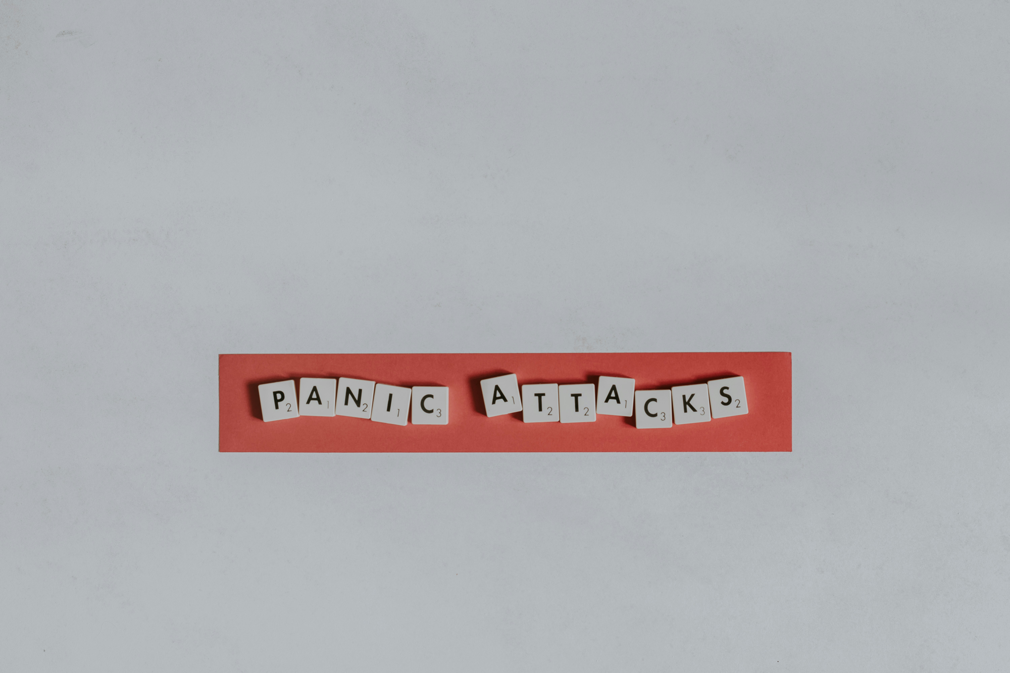 Litere Scrabble care formează cuvintele Panic Attacks pe un fond roșu
